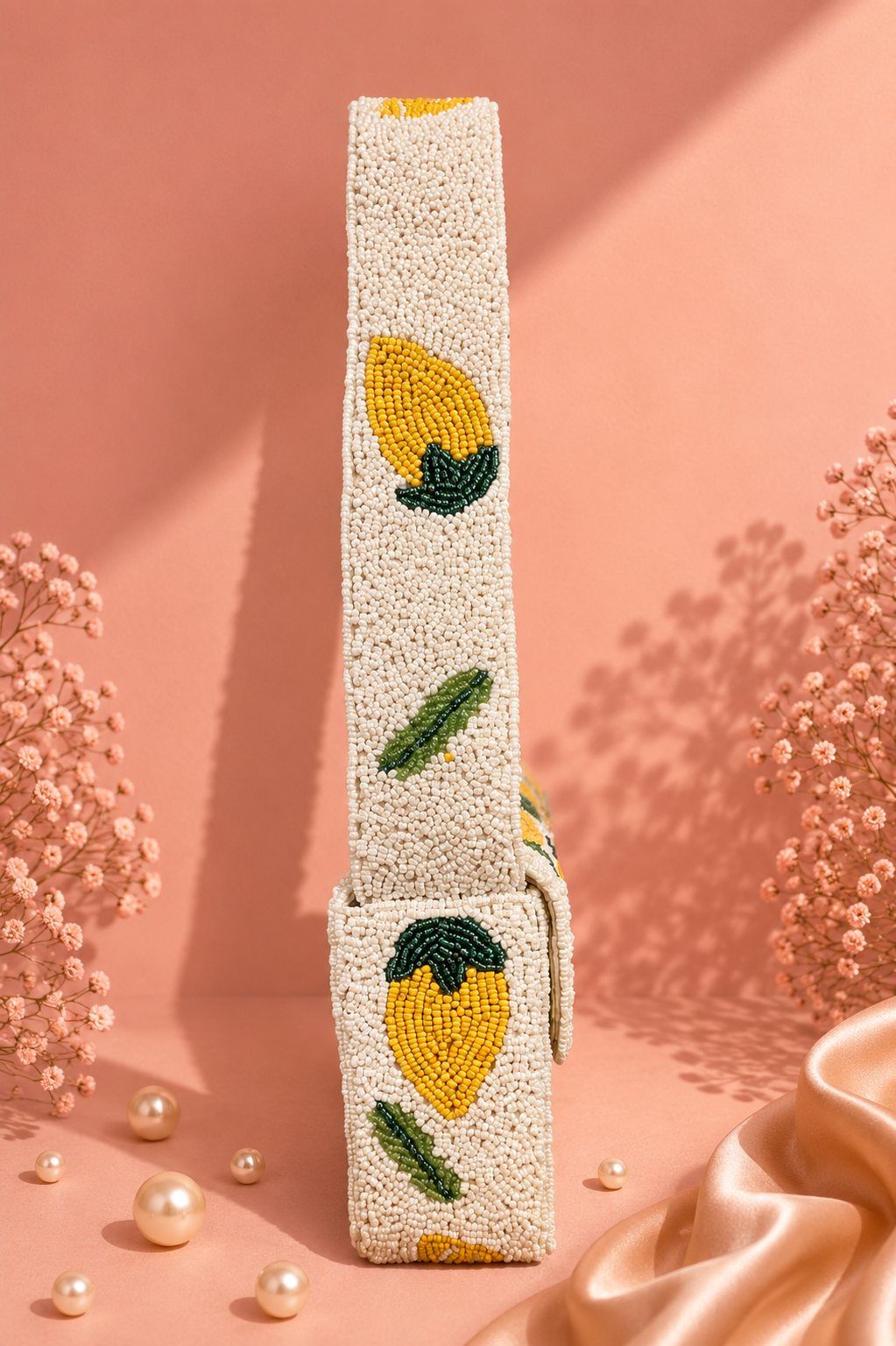 Handmade Lemon Beaded Shoulder Bag for Women | Luxury Fruit Vacation Handbag — A beaded belt with a lemon and leaf pattern, standing upright on a peach-pink background with decorative dried flowers and pearls. — Zohricanada