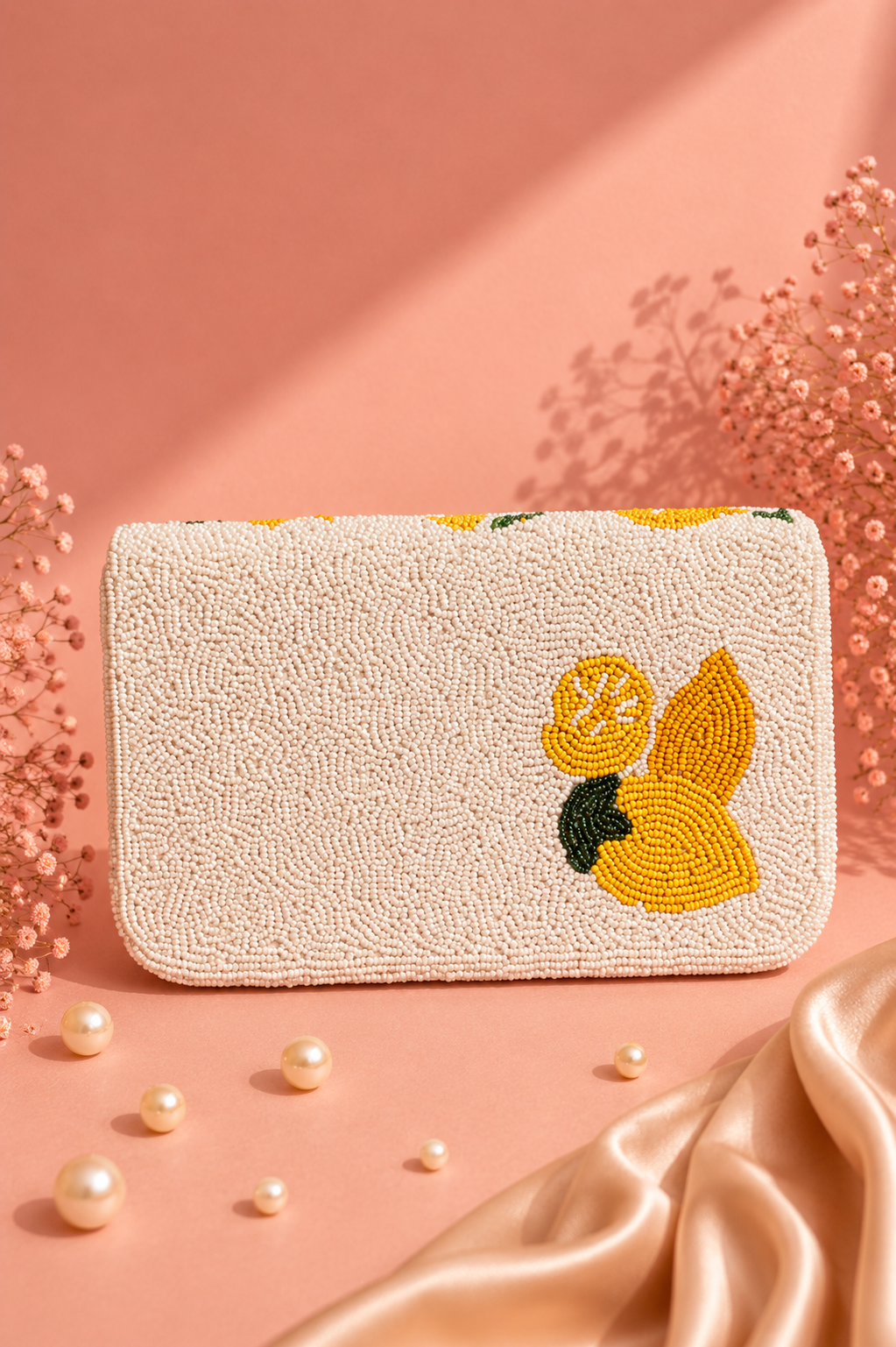 Handmade Lemon Beaded Shoulder Bag for Women | Luxury Fruit Vacation Handbag — A rectangular cream beaded clutch bag featuring a yellow and green lemon beaded motif on the front, styled on a pink background with pearls and satin fabric. — Zohricanada