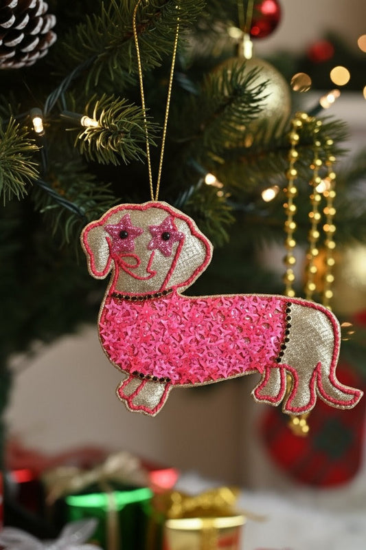 Pink Dachshund Ornament — A pink and beige dachshund-shaped sequin Christmas ornament hanging from a gold string on a decorated Christmas tree. — Zohricanada
