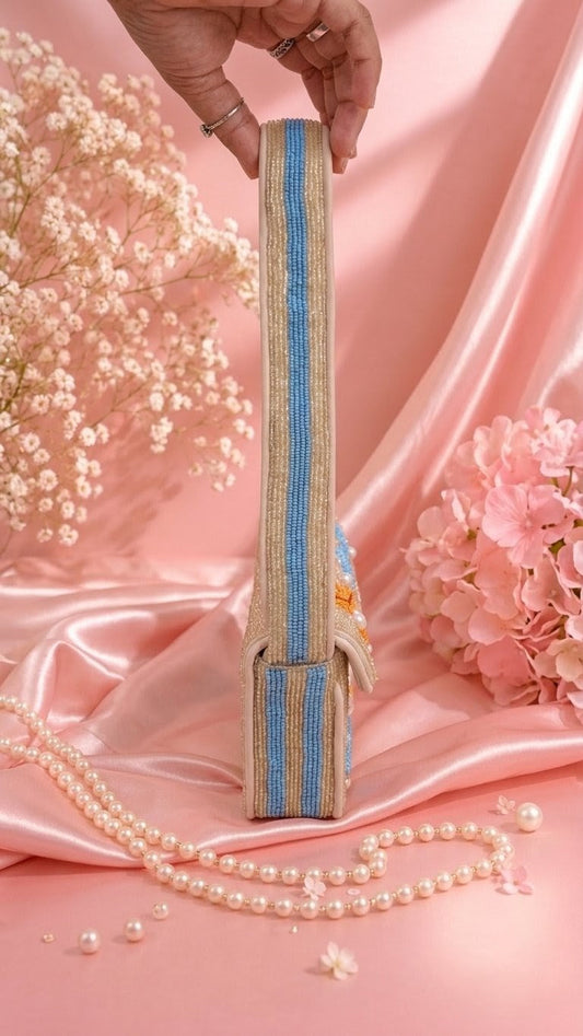Oh my Star Fish Beach bag — A hand holds a narrow, vertically oriented handbag with a beige woven body and bold blue stripes, styled on pink satin with flowers and pearl strands. — Zohricanada