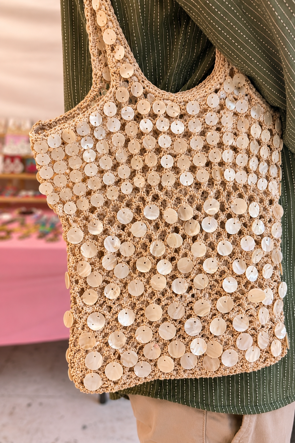 Handmade Mother-of-Pearl Shell Crochet Tote Bag for Women | Resort & Vacation Bag — Close-up of handmade beaded pearl shell crochet tote bag by ZOHRICANADA carried over the shoulder at an outdoor market — Zohricanada