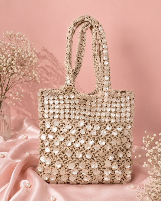 Handmade Mother-of-Pearl Shell Crochet Tote Bag for Women | Resort & Vacation Bag — Handmade beige crochet tote bag embellished with pearls and shells by ZOHRICANADA, styled on a pink satin background with flowers — Zohricanada