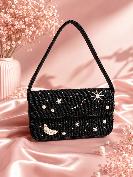 Handmade Black Beaded Celestial Evening Bag for Women | Wedding & Date Night Shoulder Bag — Black beaded shoulder bag with embroidered celestial stars and crescent moon design by ZOHRICANADA, styled on pink satin with dried flowers — Zohricanada