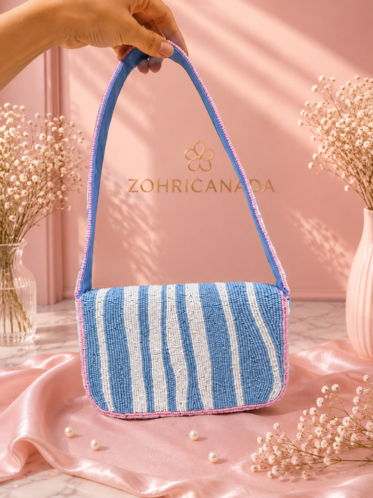 Handmade Blue & White Striped Beaded Shoulder Bag for Women | Beach & Resort Handbag — Blue and white striped beaded shoulder bag with pink trim by ZOHRICANADA, styled on a pink satin background with pearls and dried flowers — Zohricanada